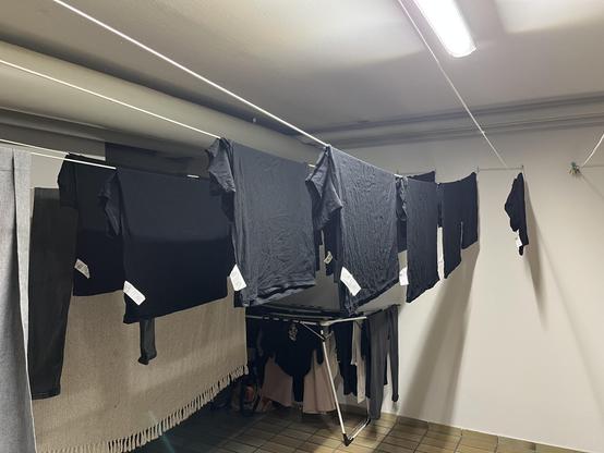 Eine Menge schwarzer auf links gedrehter Shirts hängen auf Wäscheleinen