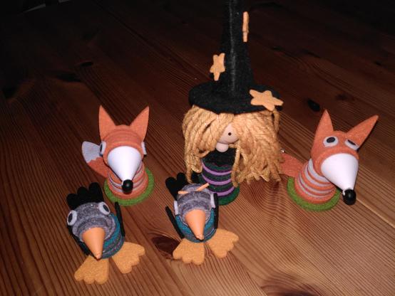 Gebastelte Figuren aus Filz-Scheiben: eine Hexe, zwei Füchse, zwei Raben.