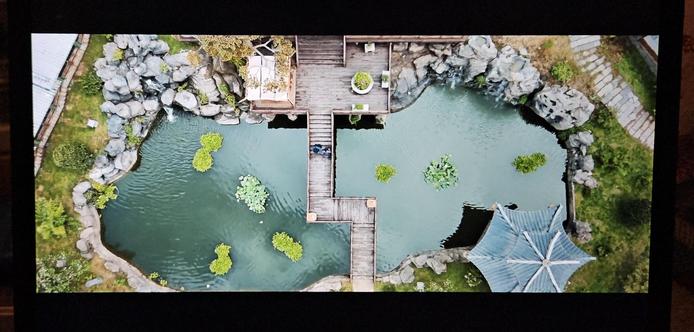 Aerial view of the landscape part of a Chinese mansion's inner courtyards. A bridge is leading over a large pond with several tufts of water lilies.