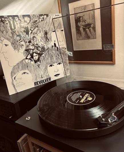 Cover of Revolver by The Beatles next to the record playing on the turntable.