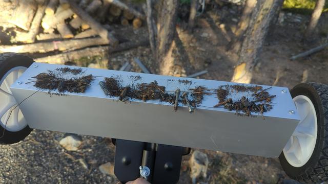A magnetic roller tool, designed to pick up metal fragments on grass/sand/gravel. It's brand new and already loaded up with metal, including a drill bit, multiple screws/acrew fragments, a star driver bit, and a spring.