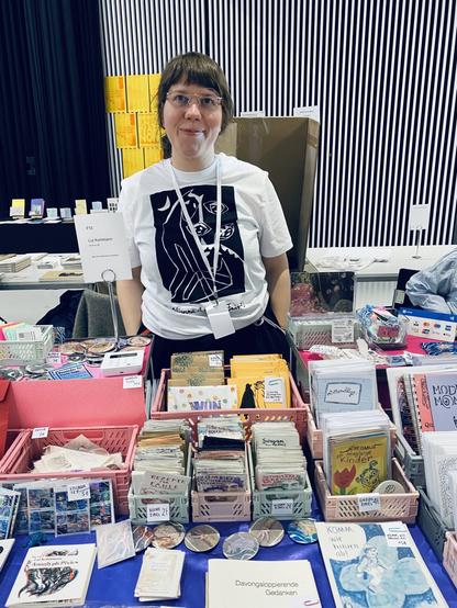 Lui hinter ihrem Stand voller Zines.