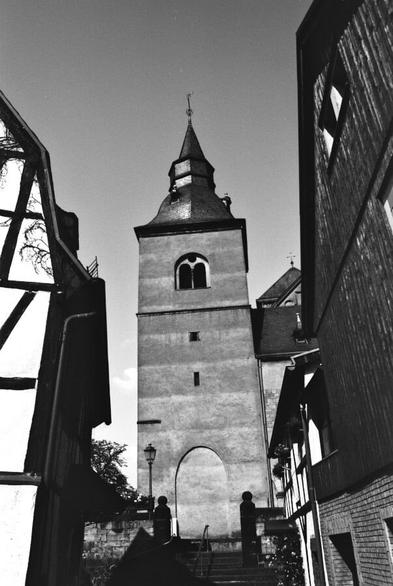 Looking up an alleyway flanked by old houses to the bell tower of St Peter and Paul's Church Remagen.