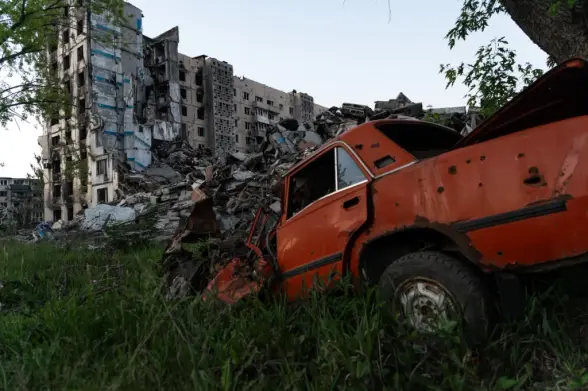 A destroyed car and residential buildings in the city of Vuhledar, Donetsk Oblast, Ukraine, in June 2024. (Yevhen Borisovskyi / The Kyiv Independent)