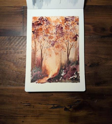 This is an Atmospheric Watercolor Landscape Painting in portrait orientation in an A5 sketchbook using Daniel Smith Rose of Ultramarine, Undersea Green, and Quinacridone Deep Gold.  There are dark hues along and below the horizon line with a little path of gold at center left. On either side of the path are slightly diluted Rose of Ultramarine and Undersea green. At the horizon line there are some dark bleeds upward but mostly gold, rose, and brown. There are trees with gold and rose leaves and the atmosphere is a pale golden and feels very sunlit.
