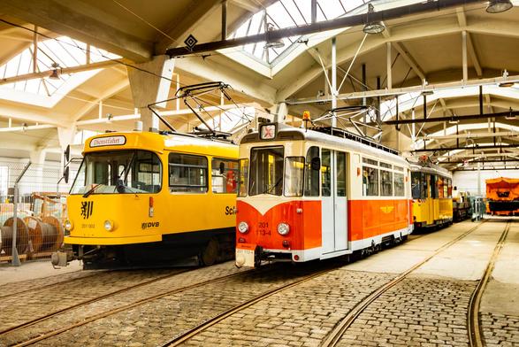Ein gelber und ein orangener Straßenbahnwagen stehen in einem Betreibshof