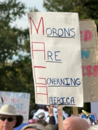 Photo by George Conway on October 18, 2025. May be an image of standing, crowd and text that says 'MoRONS M ID ARE RE N SS OVERNING PEOFLE DONT NOT PONT NT +Card MERICA'.