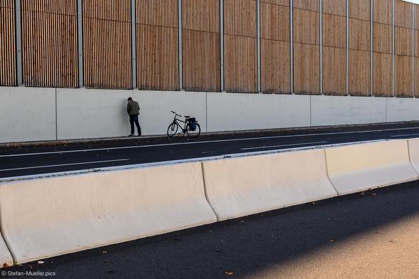 Mann uriniert auf A100. Neben ihm sein Fahrrad. Fahrraddemo auf dem gerade eingeweihten 16. Bauabschnitt der A100, Berlin, 18.10.2025