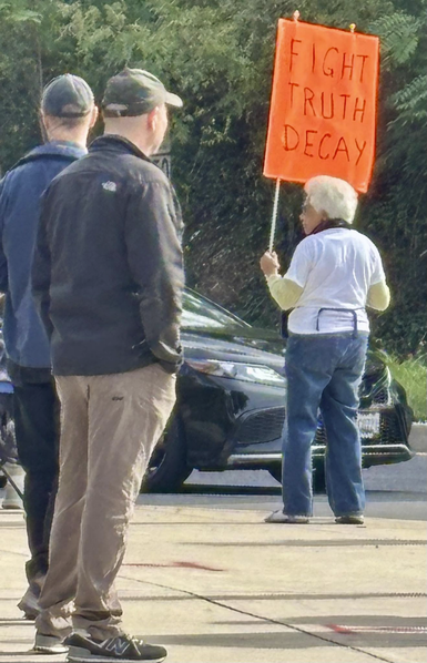 Elderly woman holding a sign that reads: "Fight Truth Decay"