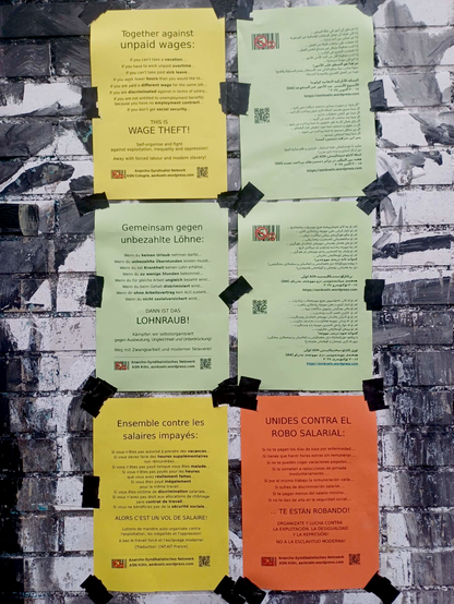 Sechs bunte, mehrsprachige Plakate gegen Lohnraub hängen an einer Hauswand mit Graffiti