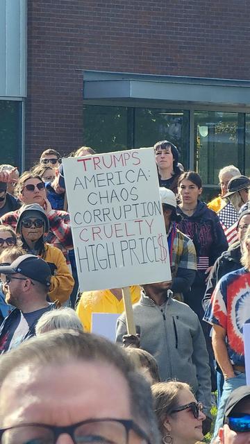 A crowd of people is gathered closely together, likely at a protest or demonstration. Several individuals are visible, with a focus on those closest to the camera. A large, rectangular sign is being held aloft in the center of the frame, partially obscuring the faces of those behind it. The sign has the following text written on it: "TRUMP’S AMERICA CHAOS CORRUPTION CRUELTY HIGH PRICES". Parts of American flags and other colorful garments are visible within the crowd.

Provided by @altbot, generated privately and locally using Gemma3:27b