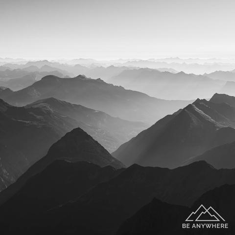 Black-and-white photo of a mountain range fading softly into the distance — calm silhouettes in mist, evoking silence and serenity