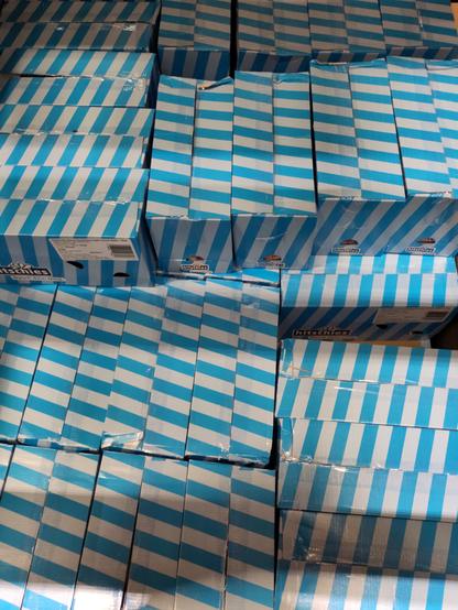 Karton gestapelt auf einer Palette, von oben gesehen. Die Kartons sind hell- und blau gestreift. Ein verwirrendes Muster entsteht.