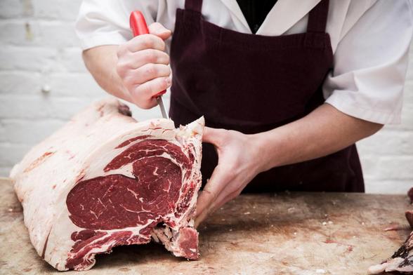 Un carnicero, partiendo una pieza de carne. (GETTY)