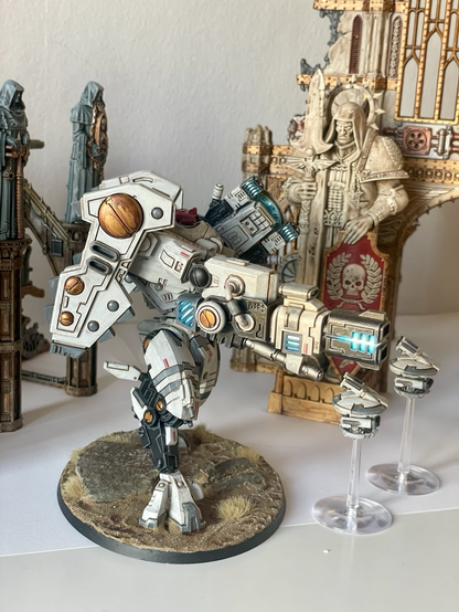 A finished riptide battlesuit with missile drones in front of sector imperialis ruins. Right hand view.