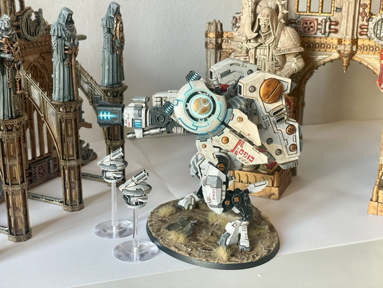 A finished riptide battlesuit with missile drones in front of sector imperialis ruins. Left hand view.