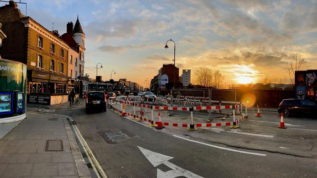 Sunset sky with orange light reflecting on buildings on a main road with roadworks.