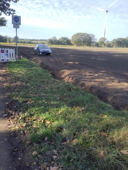 Autofahrer der eine Absperrung einer Fahrradstraße über  ein Feld umfährt.
