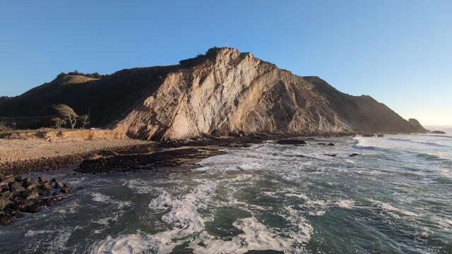 A large bluff with cliff facing, drops down into the Pacific Ocean. Looking south.