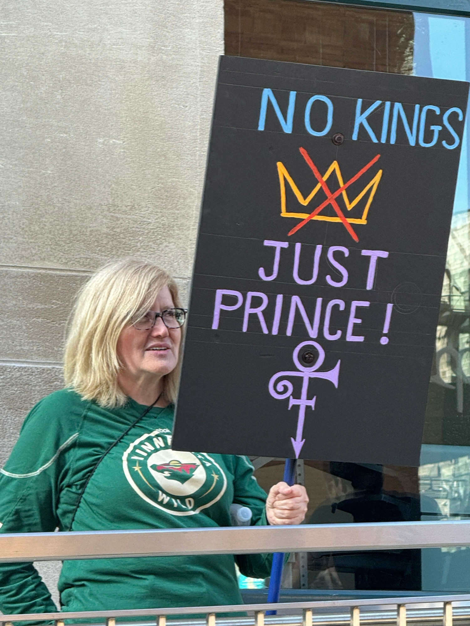 woman holding a protest sign reading NO KINGS JUST PRINCE