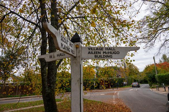 A white 'fingerpost' signpost in a small town has three arms, they say variously:
W.I. Hall
Scout Hut, Playing Field
Village Hall, Aileen McHugo Building