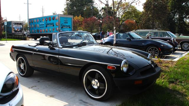Photograph of a black MGB with low-profile chrome-and-black wheels in a parking lot with a Guernsey Farms Dairy truck behind it. Did I enjoy some delicious Traverse City Cherry Java ice cream? Yes, yes I did!