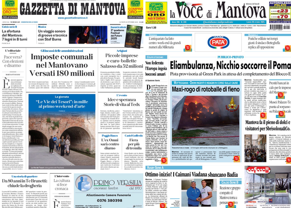 Schermata di un computer o televisore che mostra le prime pagine di due quotidiani locali italiani affiancati, la "Gazzetta di Mantova" a sinistra e "La Voce di Mantova" a destra. Gli articoli di entrambe le prime pagine trattano di notizie locali e attualità della zona di Mantova. Tra i titoli leggibili sulla Gazzetta di Mantova si nota: "Imposte comunali nel Mantovano versati 180 milioni". Sulla Voce di Mantova invece si legge: "Eliambulanza, Nicchio soccorre il Pomar", insieme a una grande immagine raffigurante probabilmente un incendio o un’esplosione, con del fumo rosso. Entrambe le testate riportano altre notizie con titoli e fotografie più piccoli, difficili da distinguere chiaramente. Tutto il resto dello sfondo è nero, evidenziando solo lo schermo acceso. Se ti serve la trascrizione completa di un articolo specifico o di altri dettagli, dimmelo pure!  .