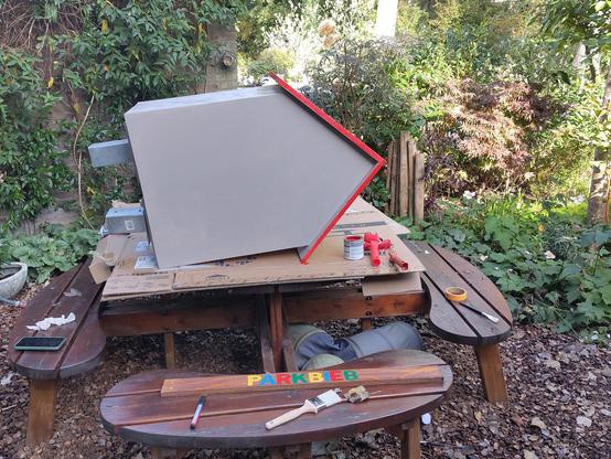 Pas geverfd kastje ligt in de tuin op de picknicktafel te drogen, met de achterzijde naar ons toe.
Lief heeft de eerste lagen aangebracht. Ik ga deze week verder met de decoratie. Dat moet binnen, want het wordt een natte week.