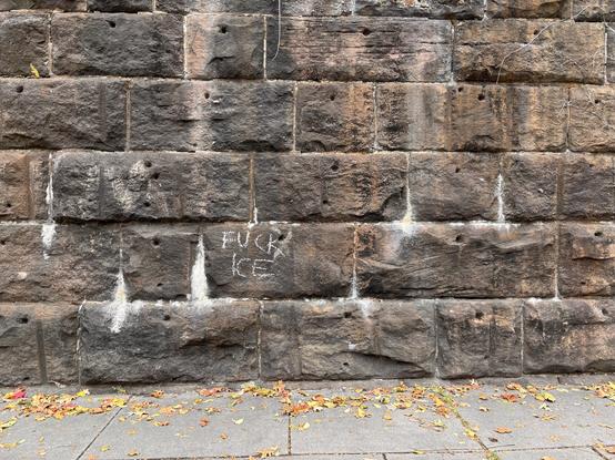 A stone wall withe the words “Fuck ICE” in chalk.