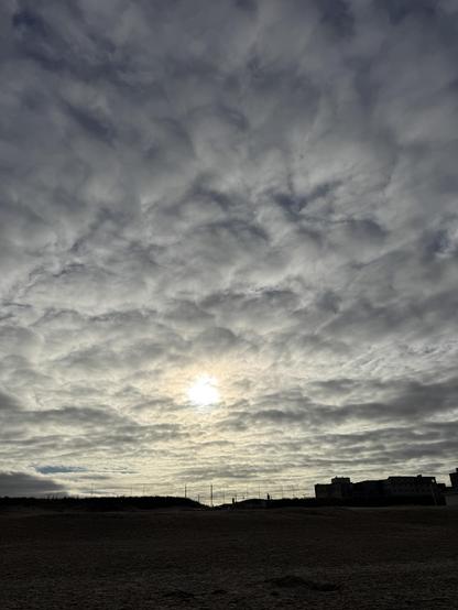 Tief stehende Sonne scheint durch eine Wolkendecke. Im unteren Bild vier sieht man scherenschnittartig einige Gebäude