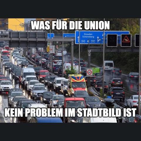Ein Bild zeigt eine Autobahnauffahrt mit dichtem Verkehr. Mehrspurige Straßen sind mit roten und weißen Autos gefüllt, die sich in beide Richtungen erstrecken. Im Vordergrund befindet sich ein gelber Straßenwartungs-Truck. Schilder über der Fahrbahn zeigen Richtungsangaben nach Dresden und Schöneberg, sowie Geschwindigkeitsbegrenzungen. Oben im Bild befindet sich ein blaues Schild mit einem Pfeil. Der Text am oberen Rand des Bildes lautet "WAS FÜR DIE UNION". Der Text am unteren Rand lautet "KEIN PROBLEM IM STADTBLATT".