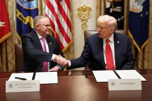 Albanese and Trump sign a rare earth minerals deal that will fuel Trump’s war machine. The 2 shake hands at a desk at the signing of the agreement.