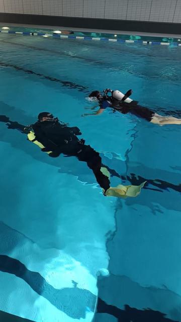 Ein Tauchlehrer taucht beim Schnuppertauchen mit einem Kind im Hallenbad.