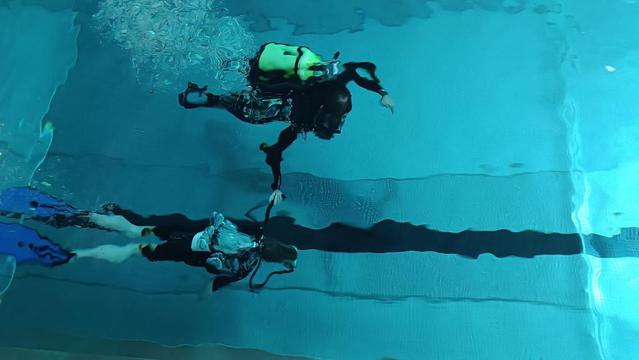 Ein Tauchlehrer taucht beim Schnuppertauchen mit einem Kind im Hallenbad.