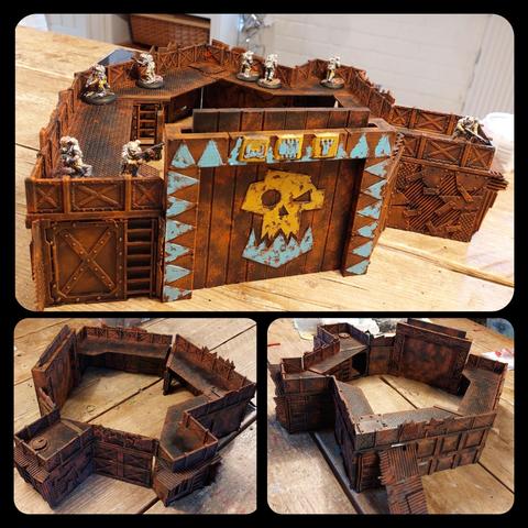 Spectacularly large gorkamorka fort (at least by my standards) made of what looks to be bulkhead screens, ladders, scraps of metal, teardrop plates and corrugated iron. It's got a giant gate that has a giant orc face on and the elements that have been not painted in rust are painted as yellow or blue elements with rust baking through. There are 8 necromunda fellas on top of it but they're barely visible even though painted in white and yellow.
