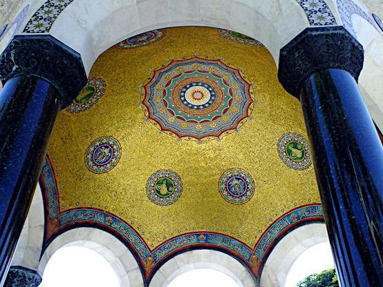 Foto van de binnenkant van een koepel met deels goudkleurig mozaïek op blauwe zuilen