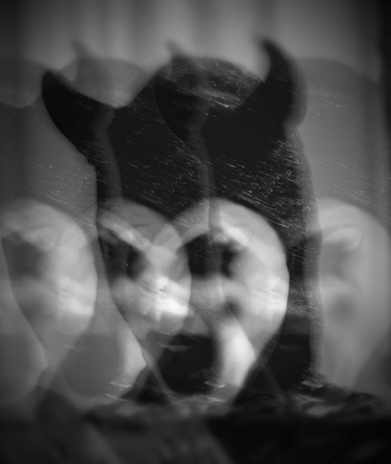 black and white image of a distorted devil face caked with circus makeup.