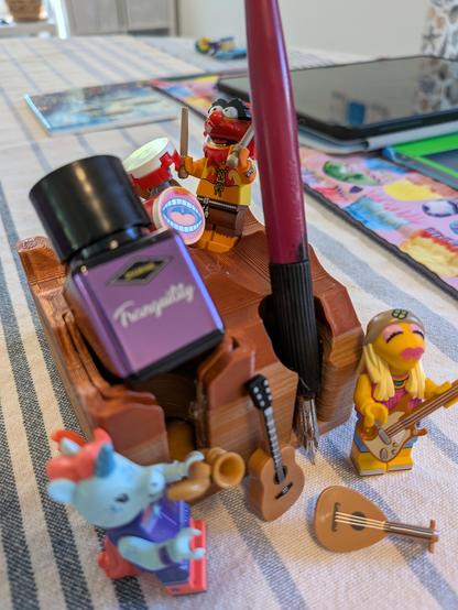 All the focus is on Animal from the Muppet band and his drum kit, standing on the rear corner of the ink stand. The Tranquility Ink and a dip pen are featured, also Janice minifig with a guitar, a minifig unicorn saxophonist completes the trio, and a lute and guitar lego instruments are lying about.