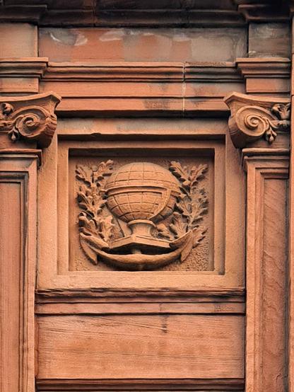 A relief sculpture of a globe and anchor surrounded by oak branches.