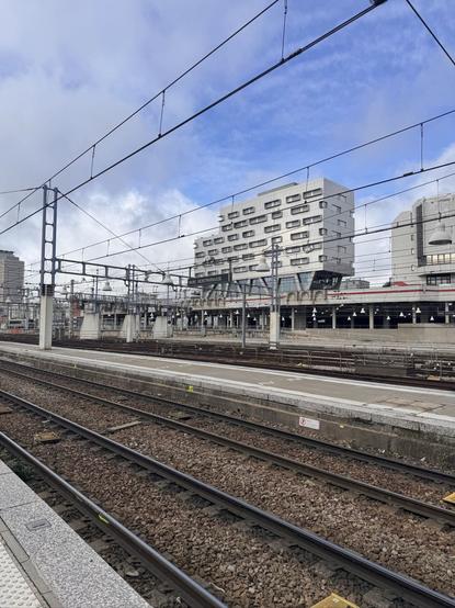 Un chemin de fer et des immeubles dans le fond avec un grand ciel bleu.