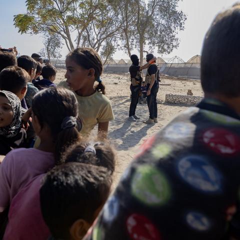 Two Hamas members during the handover of Israeli hostages in Deir al-Balah in Gaza last week, with a crowd watching.