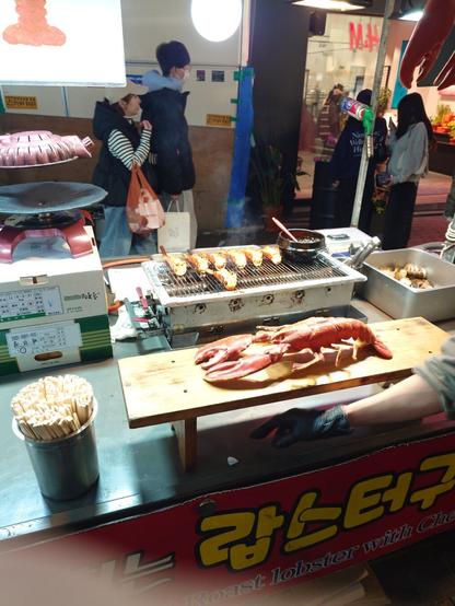 a big lobster in front of grilling smaller lobsters