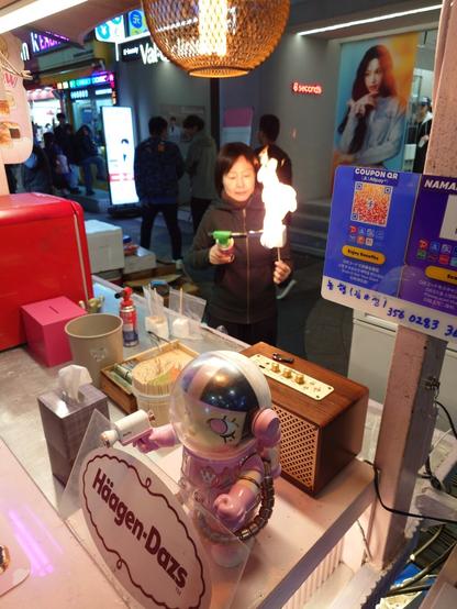 a lady is flame-burning a giant marshmallow with ice cream inside