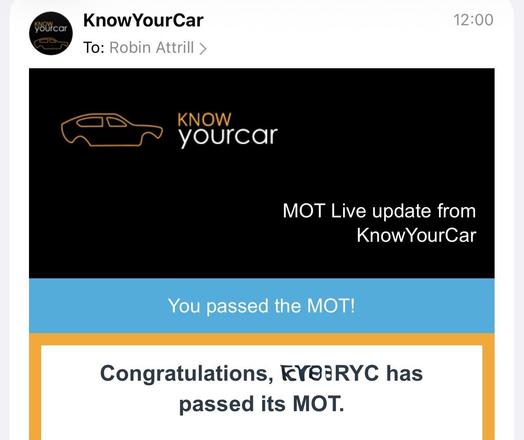 The image shows a mobile notification from the app “KnowYourCar” regarding a passed MOT test. The top portion of the notification is dark grey with a white outline of a car on the left and the text “KnowYourCar” in white below it. Below that is a line of text stating “MOT Live update”. The bottom portion of the notification is a gradient of blue and orange, with the text “You passed the MOT!” in white. Finally, below that, in a similar style, it states “Congratulations, RYC has passed its MOT.”
