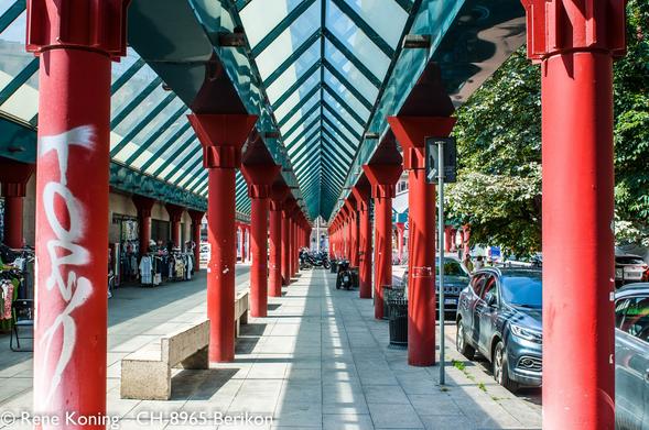 Überdachte Fussgängerpassage in Milano, links und rechts rote Säulen die eine Metallstruktur stützen.