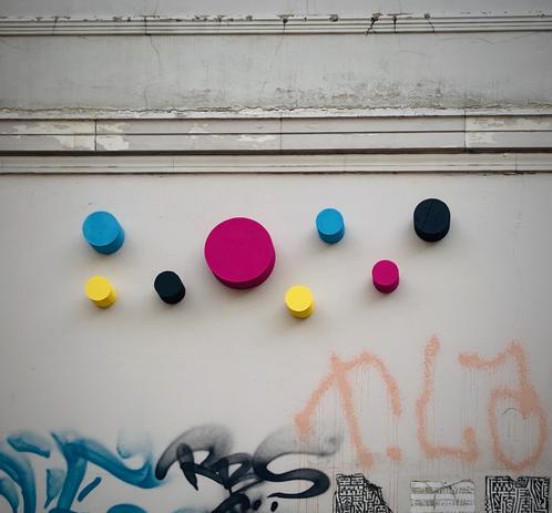 Kreise an einer Häuserwand in den Farben Cyan, Magenta, Gelb und Schwarz.