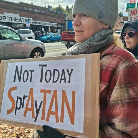 a woman holding a protest sign that says two things depending on how you read it "not today spraytan" or "not today satan"