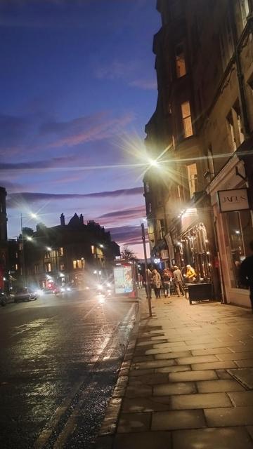Looking along Bruntsfield Place as night falls, Victorian tenements and shops on the right,  the dusk sky above a mix of pale blues, purples and pinks