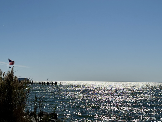 Clear, Bright blue skies. Sunlight lighting up the water on the Chesapeake bay. A US flag flowing in the breeze.
