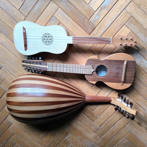 A picture of 3 instruments I have built this year, lying on a wooden herringbone floor. From top to bottom: A renaissance guitar, a ronroco (large charango) and an oud.